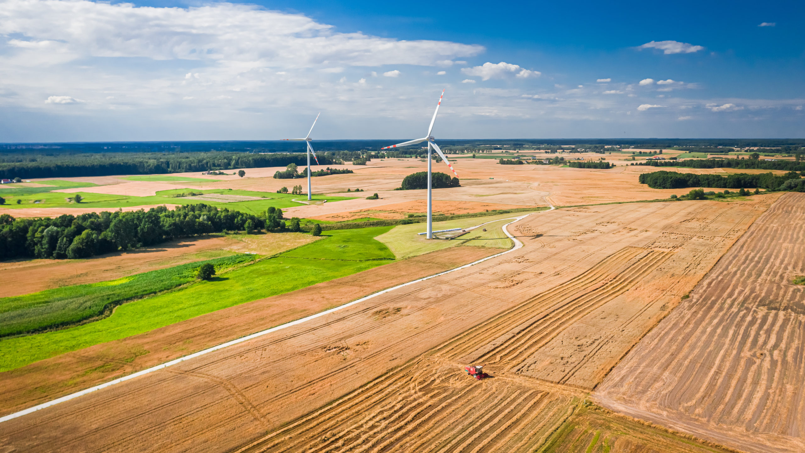 Combine during harvest on the field with wind turbines